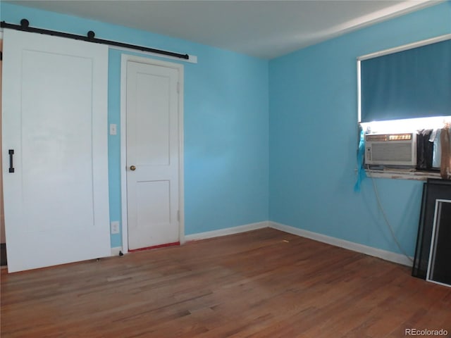 875 Kenton St, Aurora, CO 80010 - unfurnished bedroom featuring a barn door, wood finished floors, and cooling unit