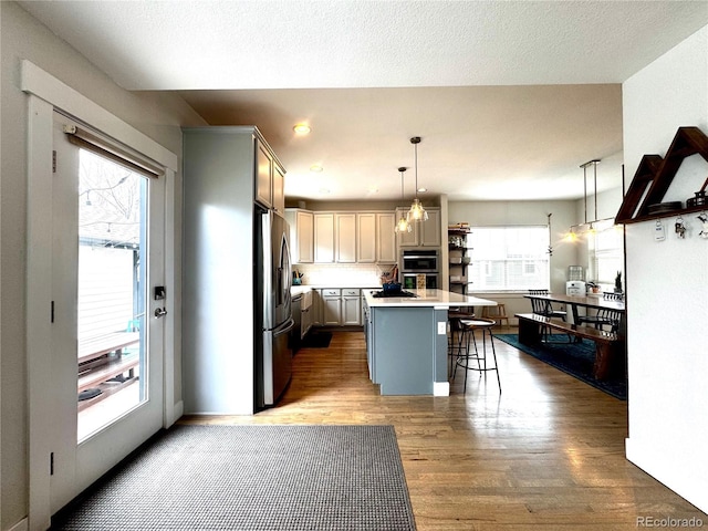 2831 Shadow Lake Rd, Lafayette, CO 80026 - kitchen featuring stainless steel appliances, a breakfast bar, wood finished floors, a center island, and light countertops
