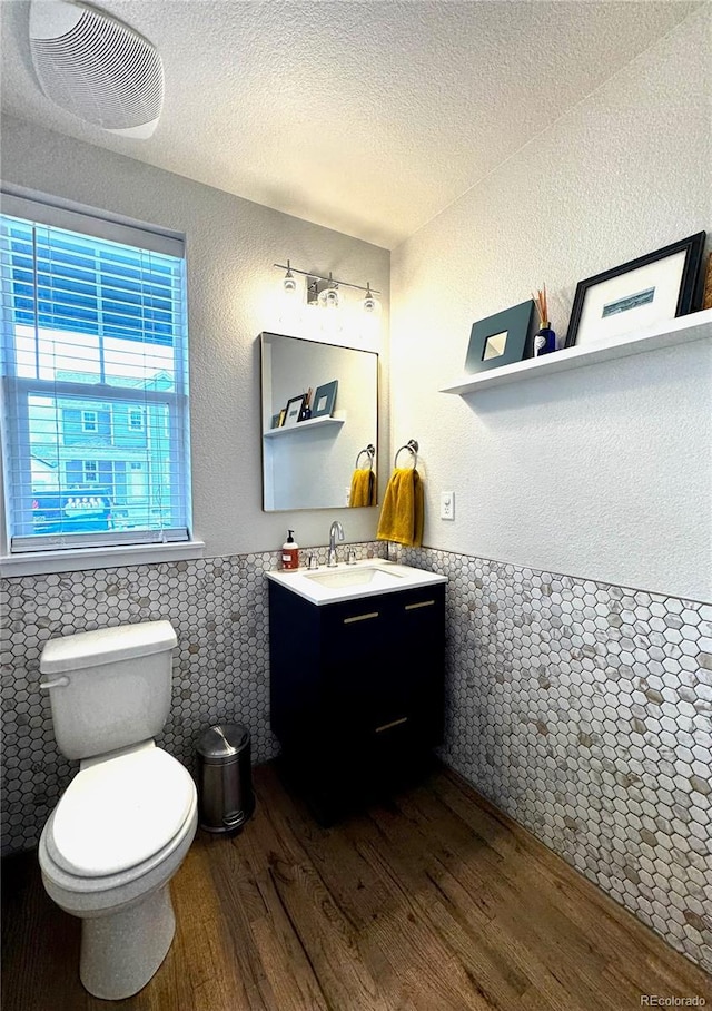 2831 Shadow Lake Rd, Lafayette, CO 80026 - half bathroom featuring wood finished floors, vanity, tile walls, toilet, and wainscoting
