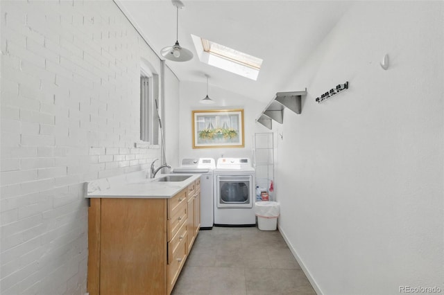 washroom with light tile patterned floors, cabinet space, a skylight, a sink, and washing machine and dryer