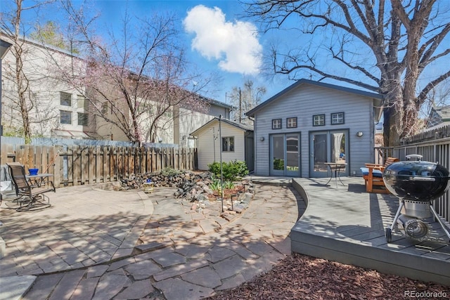 back of property featuring fence, a patio, and a wooden deck