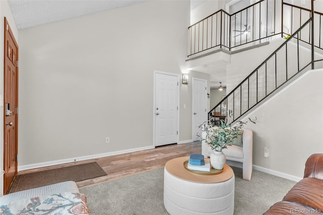 living room with stairs, a high ceiling, baseboards, and wood finished floors