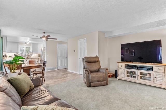 living room featuring a textured ceiling, a ceiling fan, and baseboards