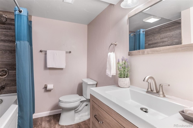 bathroom with toilet, wood finished floors, baseboards, vanity, and shower / bath combo