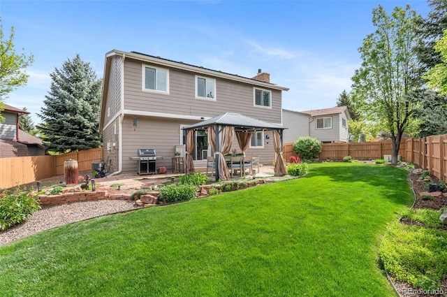 rear view of property featuring a gazebo, a patio area, a chimney, and a garden