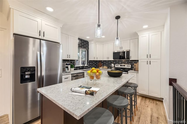 10751 W 66th Ave, Arvada, CO 80004 - kitchen featuring backsplash, a kitchen bar, light wood-type flooring, white cabinets, and stainless steel appliances