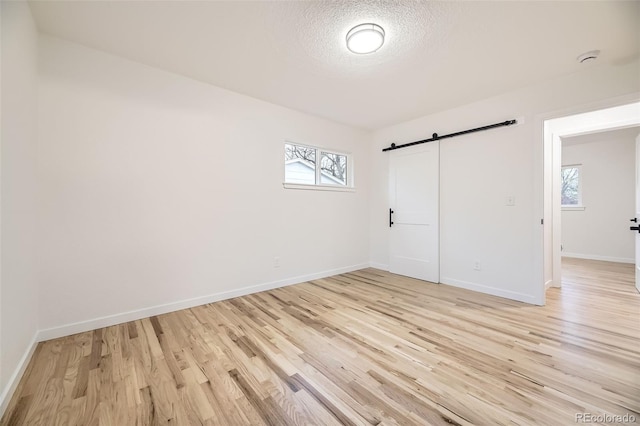 10751 W 66th Ave, Arvada, CO 80004 - unfurnished bedroom featuring baseboards, a barn door, multiple windows, and light wood-style floors