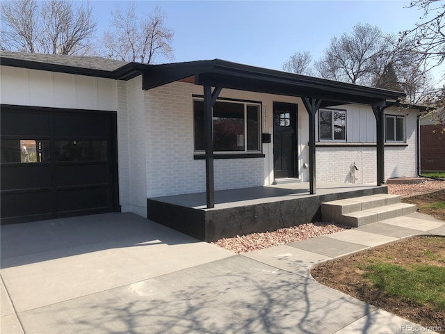 10751 W 66th Ave, Arvada, CO 80004 - view of front facade with brick siding, a garage, board and batten siding, concrete driveway, and covered porch
