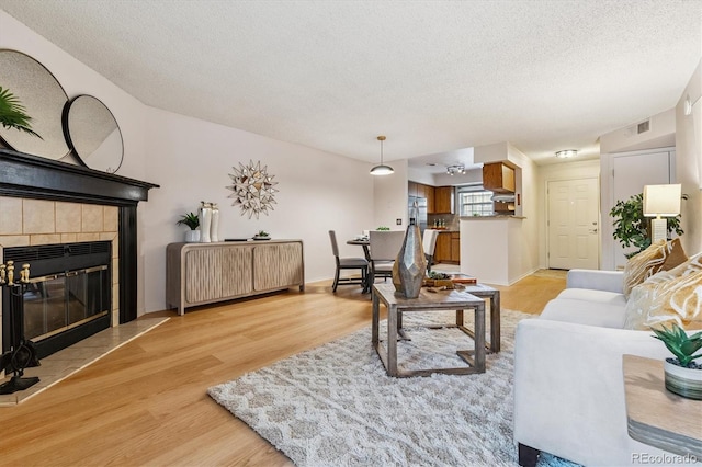 2710 E Otero Pl Unit 6, Centennial, CO 80122 - living area with light wood-type flooring, a textured ceiling, and a tile fireplace