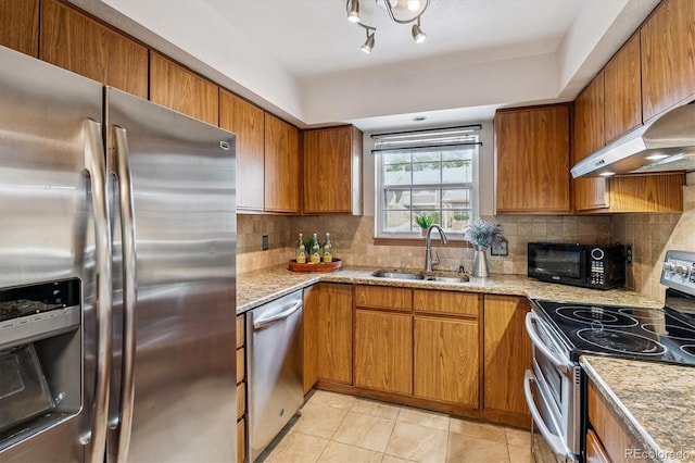 2710 E Otero Pl Unit 6, Centennial, CO 80122 - kitchen with stainless steel appliances, brown cabinetry, under cabinet range hood, backsplash, and light stone countertops