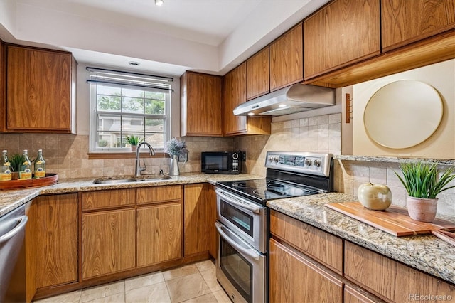 2710 E Otero Pl Unit 6, Centennial, CO 80122 - kitchen with stainless steel appliances, under cabinet range hood, decorative backsplash, light stone countertops, and brown cabinetry