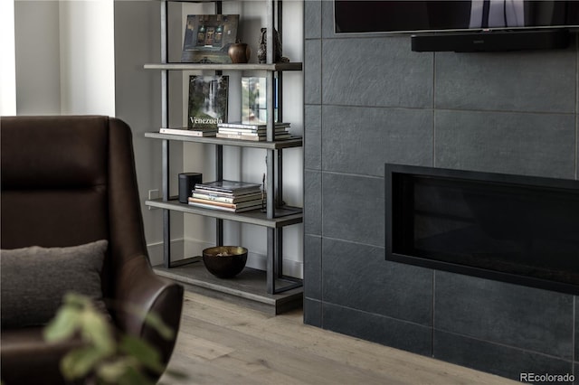 interior details with wood-type flooring and a tile fireplace