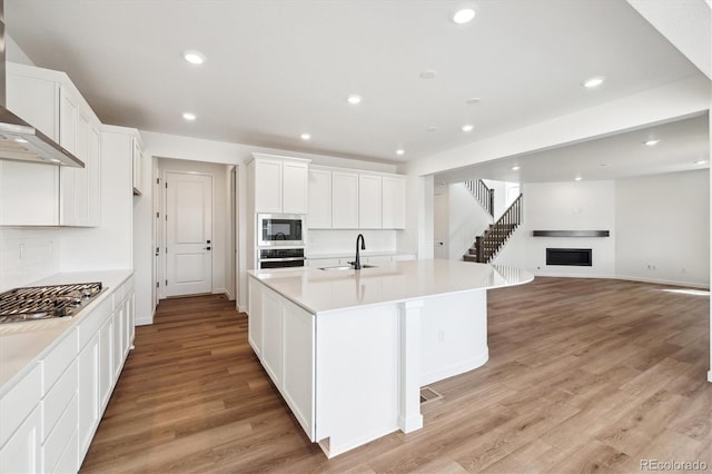 24748 E 40th Ave, Aurora, CO 80019 - kitchen with a sink, wall chimney exhaust hood, stainless steel appliances, light wood-type flooring, and white cabinets