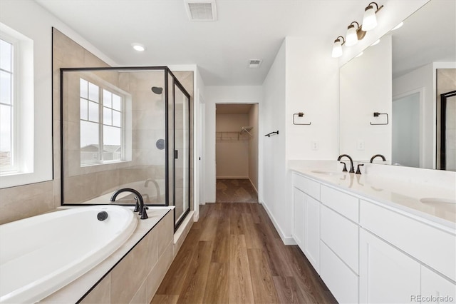 24748 E 40th Ave, Aurora, CO 80019 - bathroom featuring a stall shower, a bath, wood finished floors, a spacious closet, and double vanity