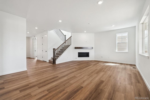 24748 E 40th Ave, Aurora, CO 80019 - unfurnished living room with a glass covered fireplace, wood finished floors, stairway, baseboards, and recessed lighting