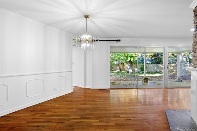 unfurnished room featuring an inviting chandelier, hardwood / wood-style floors, and ornamental molding