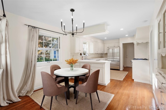 dining area with light hardwood / wood-style floors, sink, and an inviting chandelier