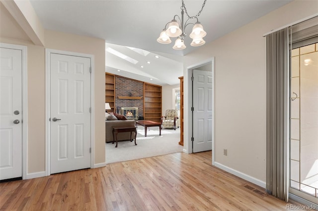 874 Mercury Cir, Lone Tree, CO 80124 - interior space featuring built in features, vaulted ceiling, a brick fireplace, light wood finished floors, and a chandelier