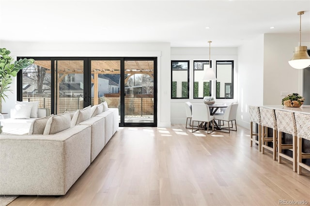 living area featuring recessed lighting, plenty of natural light, light wood-style flooring, and baseboards