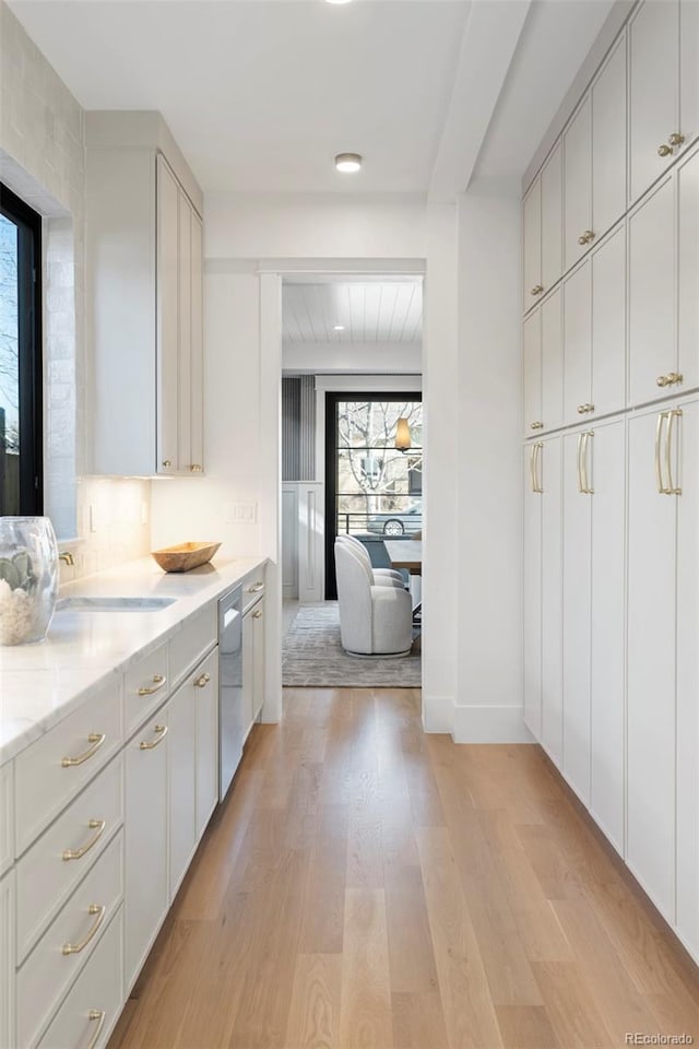 kitchen featuring a sink, light wood-style floors, white cabinetry, and dishwasher