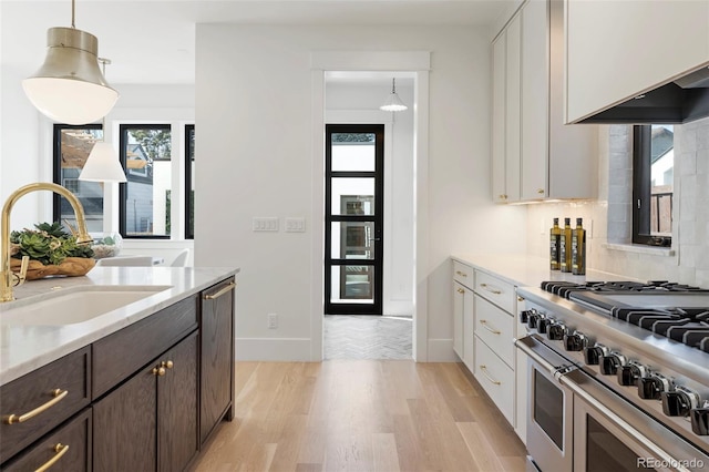 kitchen featuring dark brown cabinetry, appliances with stainless steel finishes, hanging light fixtures, white cabinetry, and a sink