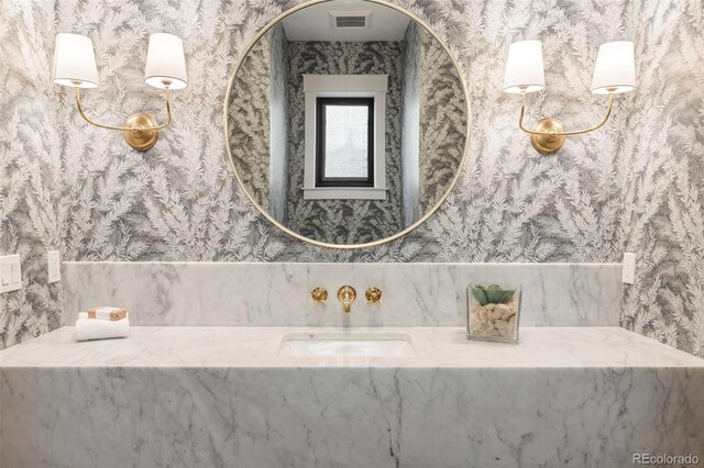 bathroom with visible vents, a sink, and wallpapered walls