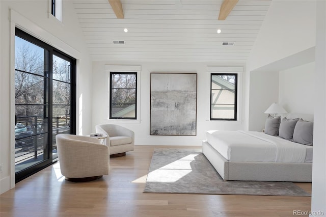 bedroom with light wood-style flooring, multiple windows, high vaulted ceiling, and beam ceiling