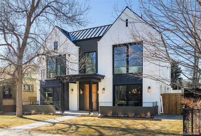 view of front of home featuring a standing seam roof, fence, and metal roof