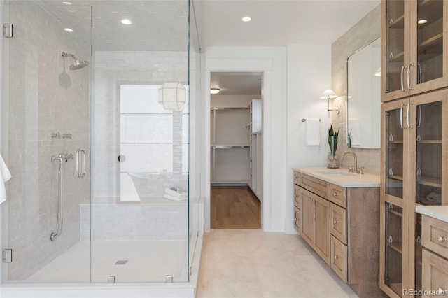 bathroom featuring a stall shower, a walk in closet, and vanity