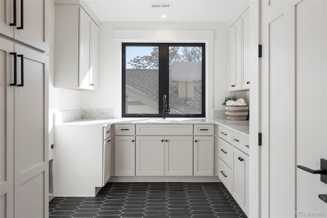 kitchen featuring light countertops, a sink, visible vents, and white cabinetry