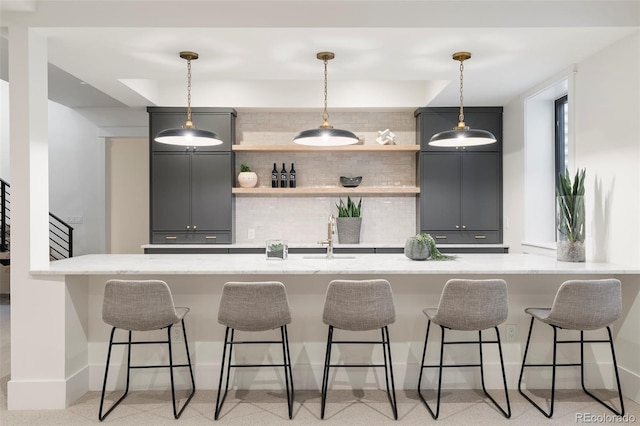 kitchen with tasteful backsplash, a kitchen bar, pendant lighting, and open shelves