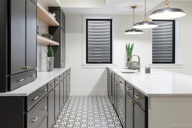 kitchen featuring baseboards, decorative light fixtures, gray cabinetry, open shelves, and a sink