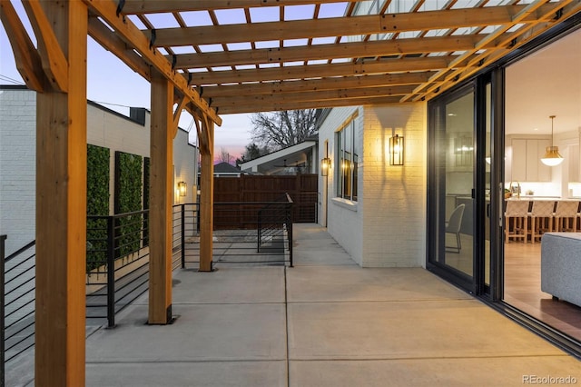 patio terrace at dusk featuring fence and a pergola