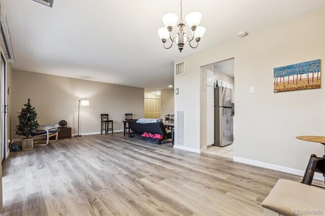 living area featuring light wood finished floors, a chandelier, and baseboards