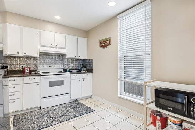 kitchen with white electric stove, under cabinet range hood, black microwave, decorative backsplash, and white cabinetry