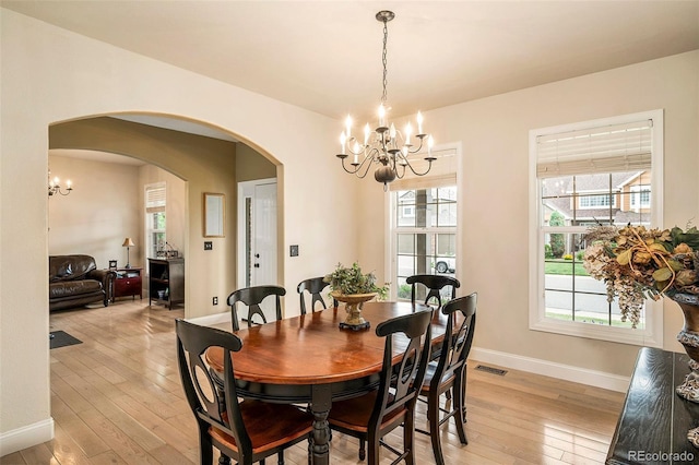 5774 S Genoa Ct, Aurora, CO 80015 - dining room featuring a chandelier, arched walkways, and light wood-type flooring