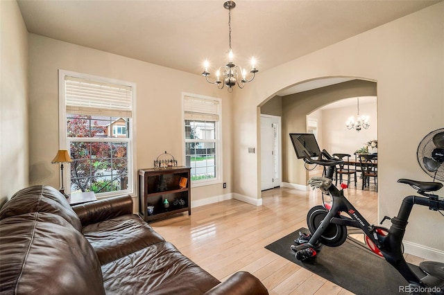 5774 S Genoa Ct, Aurora, CO 80015 - exercise room featuring a chandelier, arched walkways, and light wood-style floors