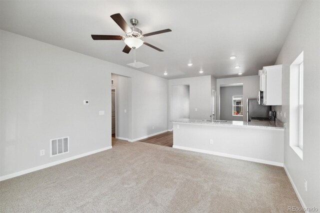 unfurnished living room with sink, dark carpet, and ceiling fan