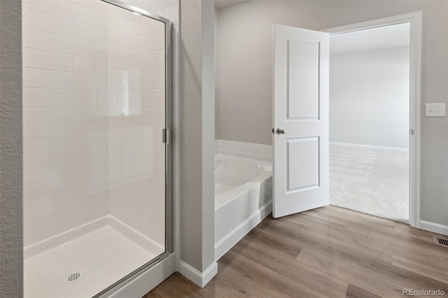 bathroom with independent shower and bath and hardwood / wood-style floors