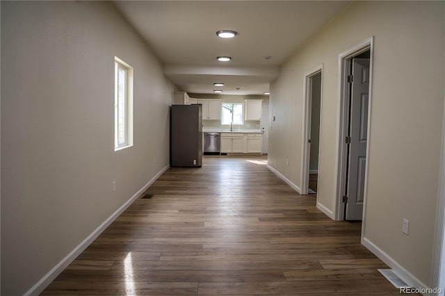 1511 E Routt St Ave, Pueblo, CO 81004 - corridor featuring visible vents, baseboards, dark wood-type flooring, and a sink