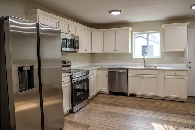 kitchen with light hardwood / wood-style flooring, stainless steel appliances, sink, and white cabinetry