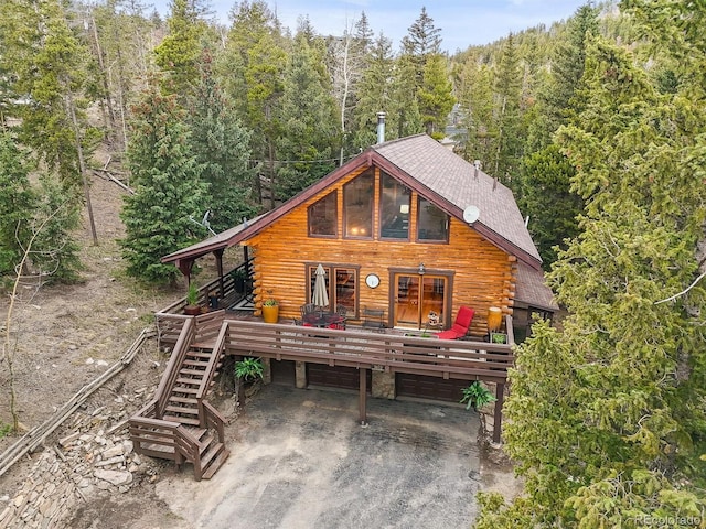 1673 Sinton Rd, Evergreen, CO 80439 - log cabin with log siding, a wooded view, driveway, and a garage