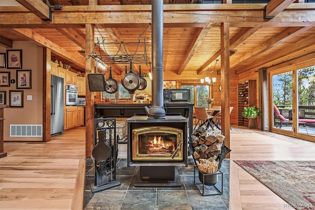 1673 Sinton Rd, Evergreen, CO 80439 - detailed view of a wood stove, wooden ceiling with exposed beams, appliances with stainless steel finishes, wood finished floors, and a chandelier
