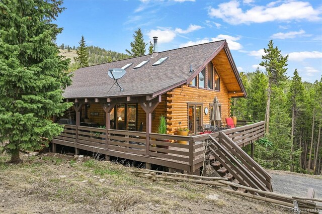 1673 Sinton Rd, Evergreen, CO 80439 - rear view of house with log exterior, roof with shingles, a wooden deck, and a forest view