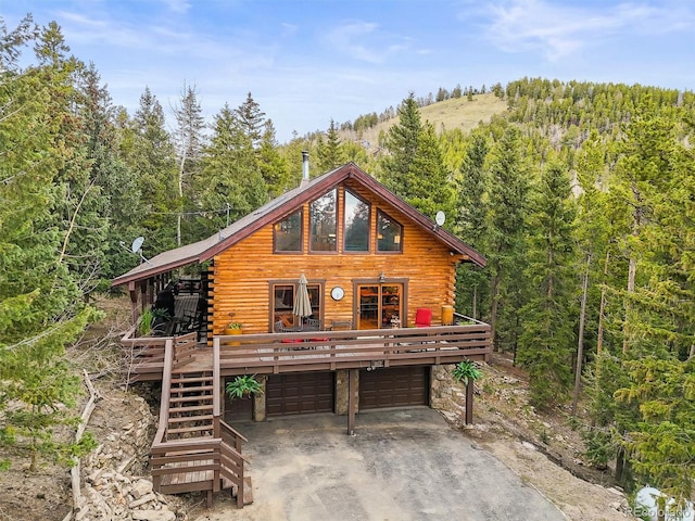 1673 Sinton Rd, Evergreen, CO 80439 - cabin with log exterior, a forest view, dirt driveway, and an attached garage