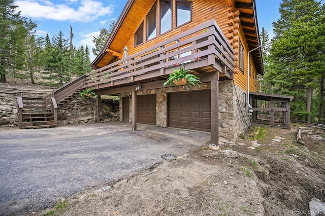 1673 Sinton Rd, Evergreen, CO 80439 - view of side of property with stone siding, an attached garage, driveway, a wooden deck, and stairway