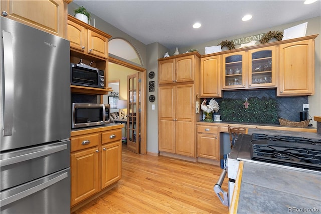 kitchen with decorative backsplash, built in desk, stainless steel appliances, and light wood-type flooring