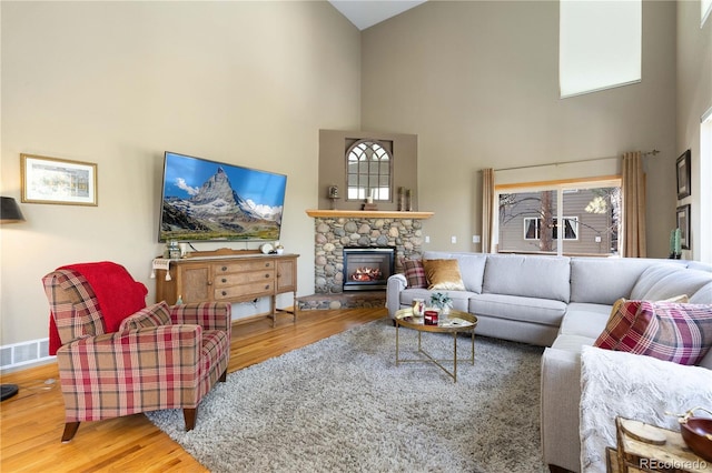 living room featuring a towering ceiling, a fireplace, and hardwood / wood-style floors