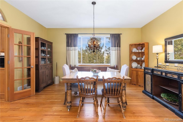 dining space with an inviting chandelier, a wealth of natural light, and light wood-type flooring