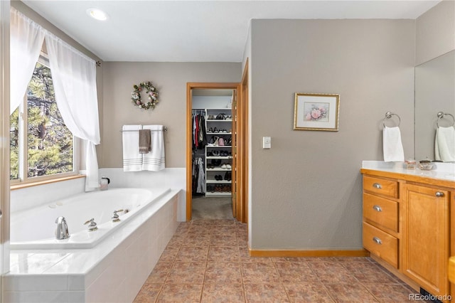 bathroom featuring tile patterned flooring, vanity, and tiled bath